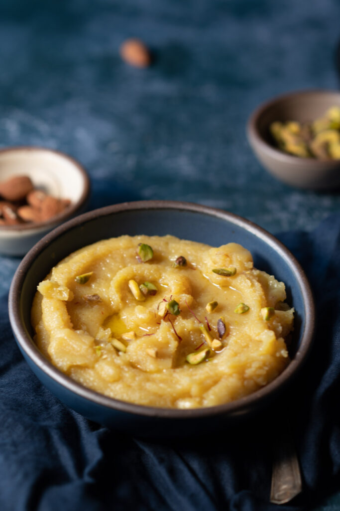 This is the final image of badam halwa made from almond flour in a blowl garnished with saffron strands and pistachio.