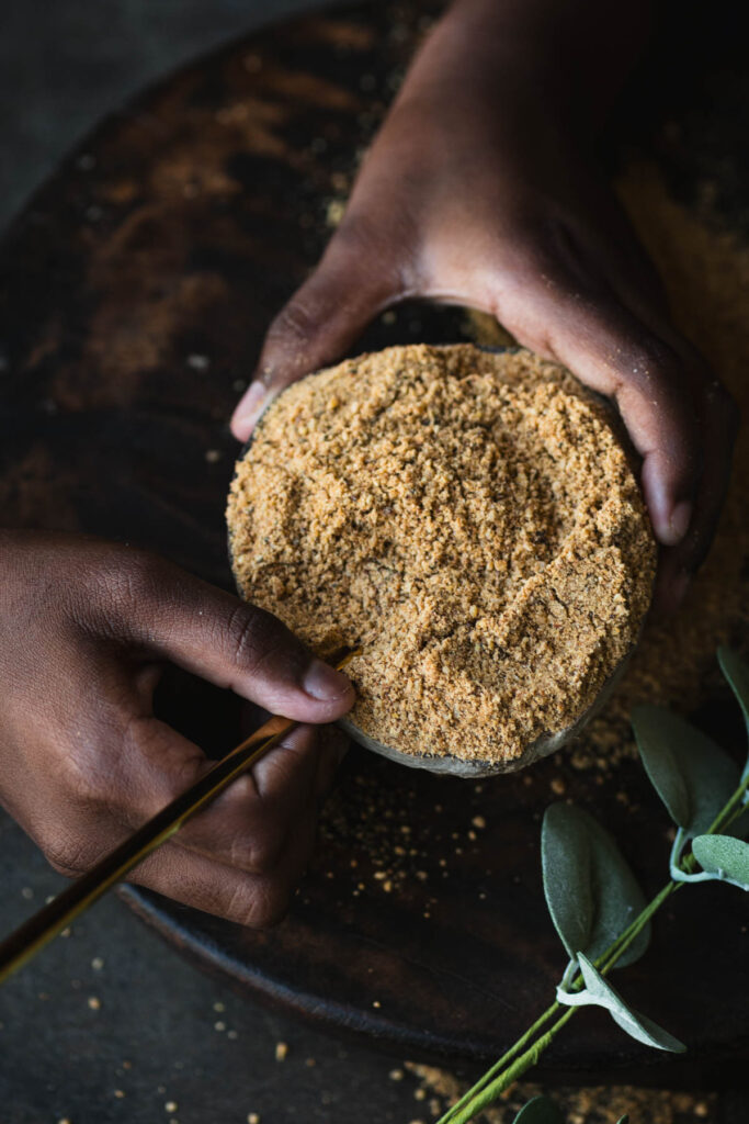 This is a picture of a girl holding Idli Podi bowl along with a spoon.