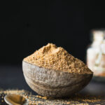 This is a hero shot of the Idli milagai podi in a rustic bowl on a rustic table