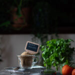 This is a picture of rasam powder blend on a cup of glass on a table .