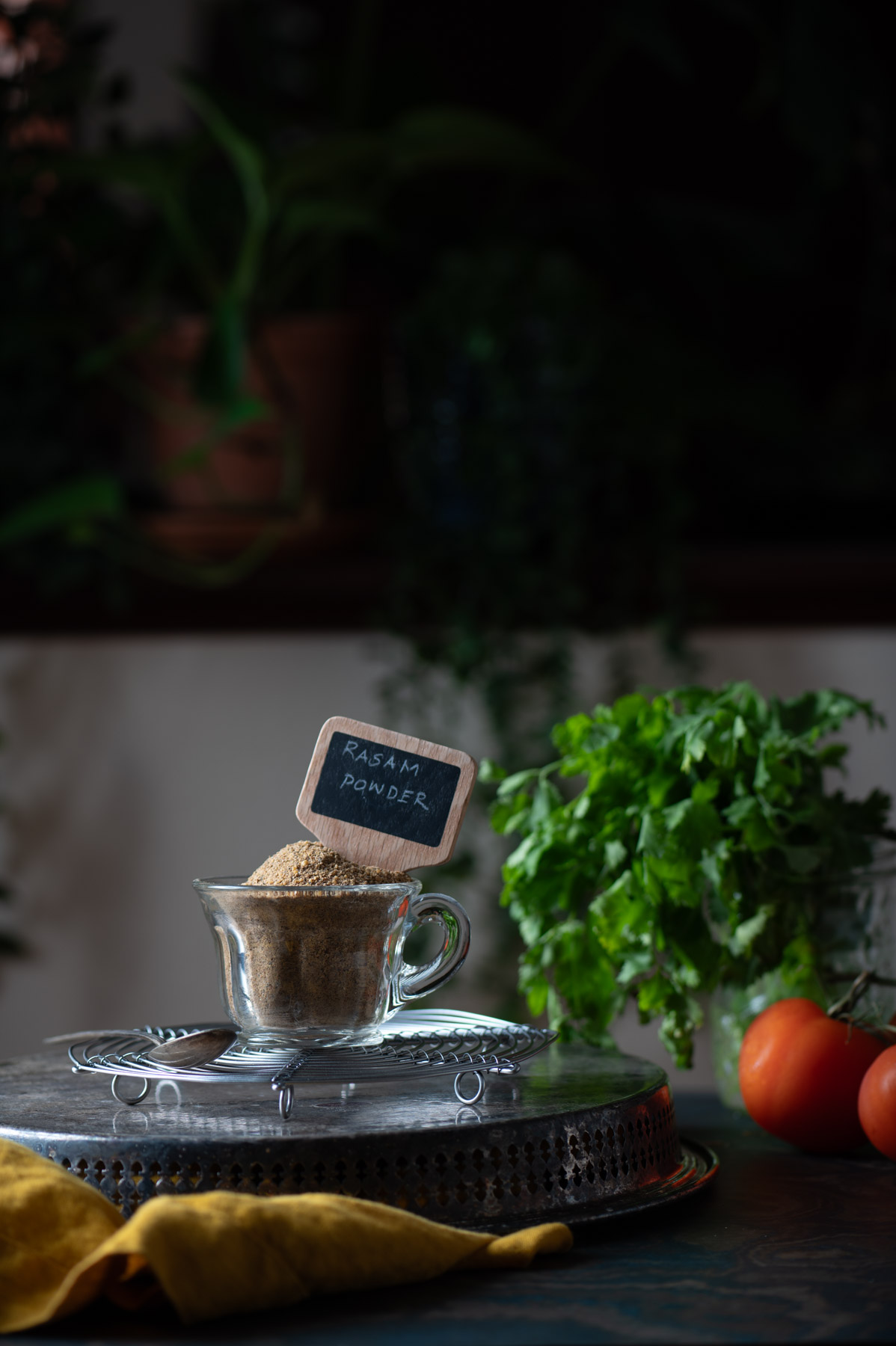 This is a picture of rasam powder blend on a cup of glass on a table .