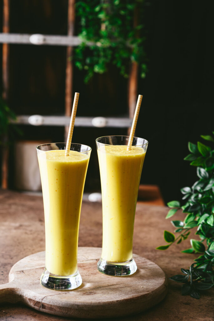 This is a picture of Saffron Pistachio Lassi served in 2 glasses with a straw.