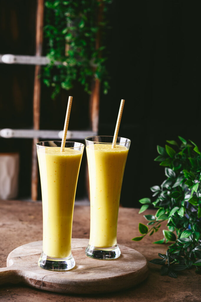 This is a picture of 2 glasses of saffron pistachio lassi on the table.