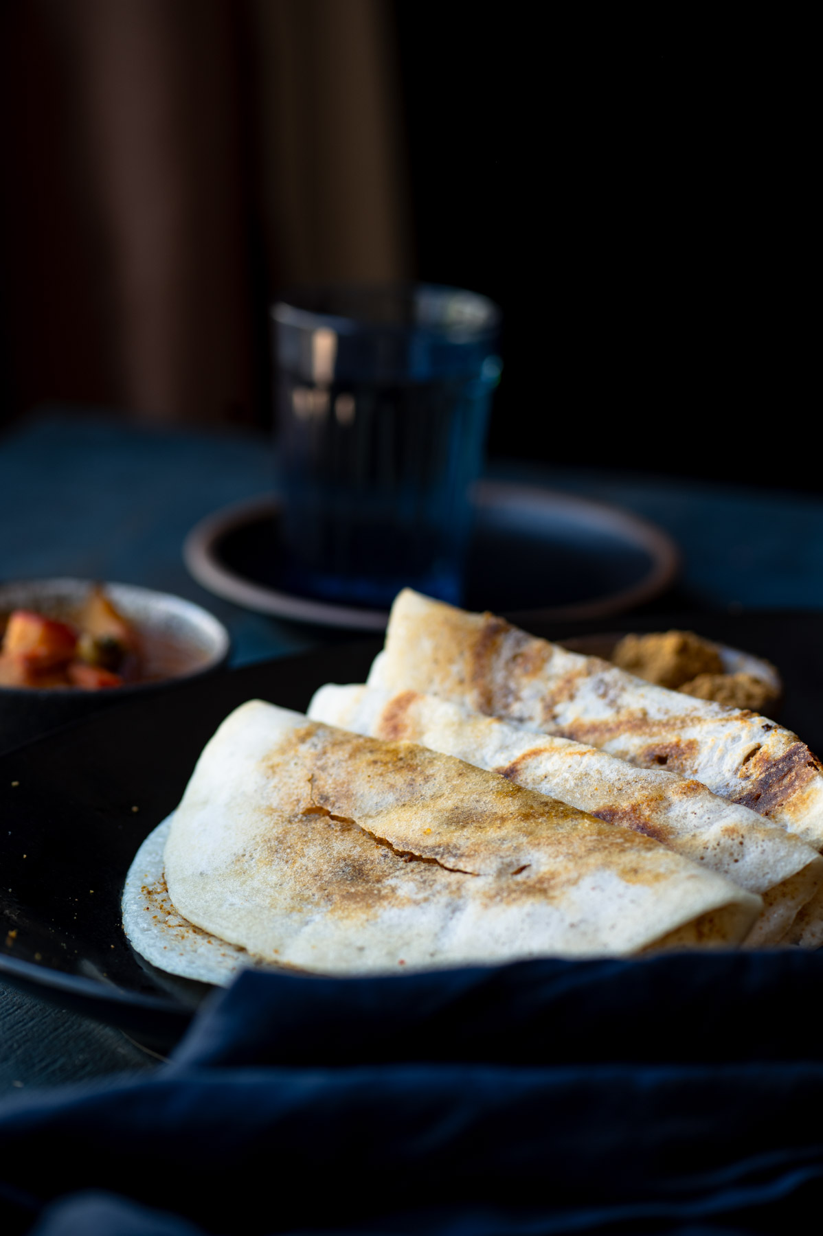 This is a picture of Podi Dosa on a plate with sambhar on the side.