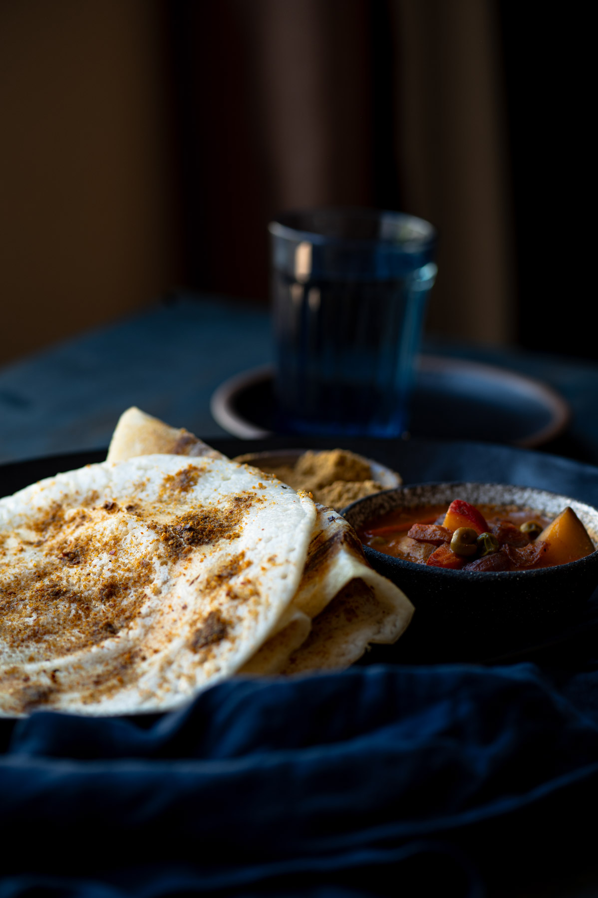 This is a picture of Podi dosa served on a plate with sambhar