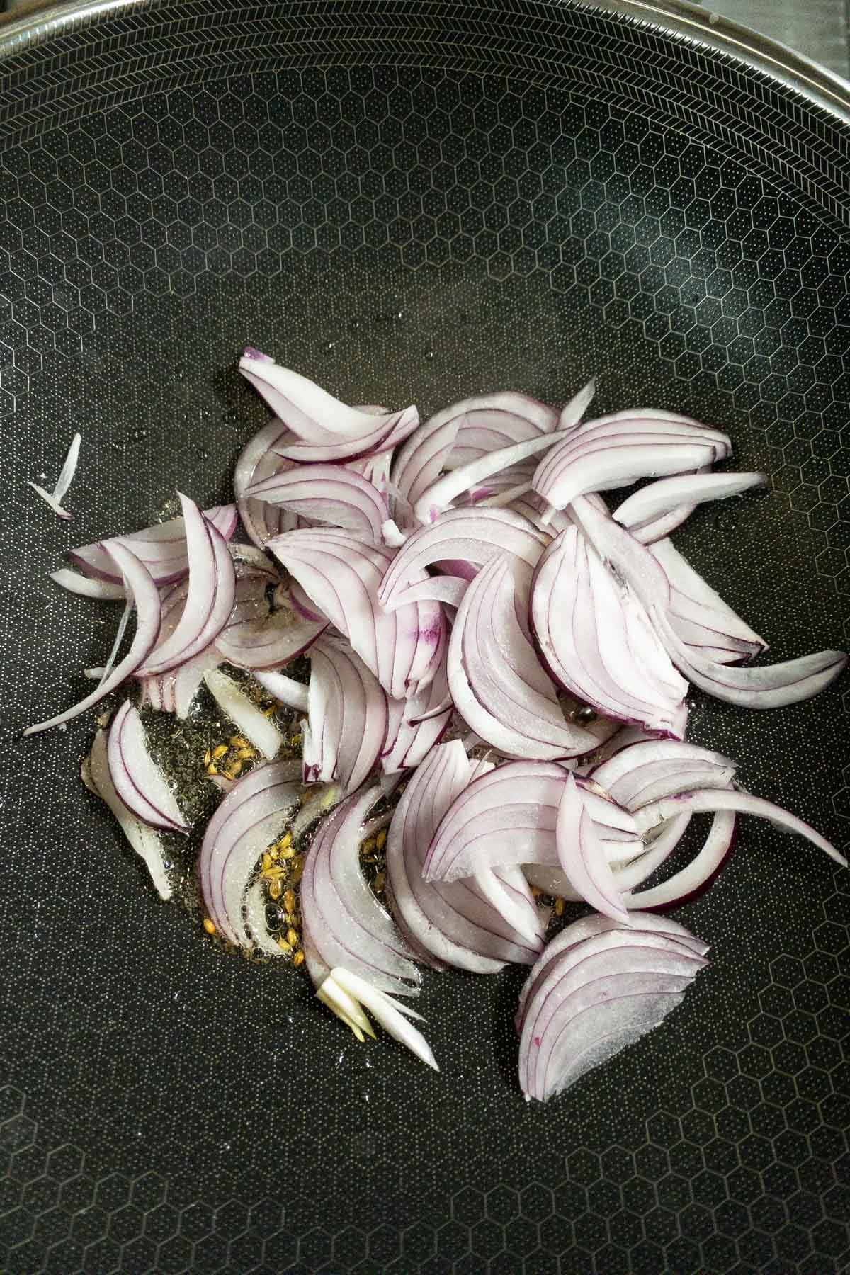 Adding sliced onions to make the egg thokku.