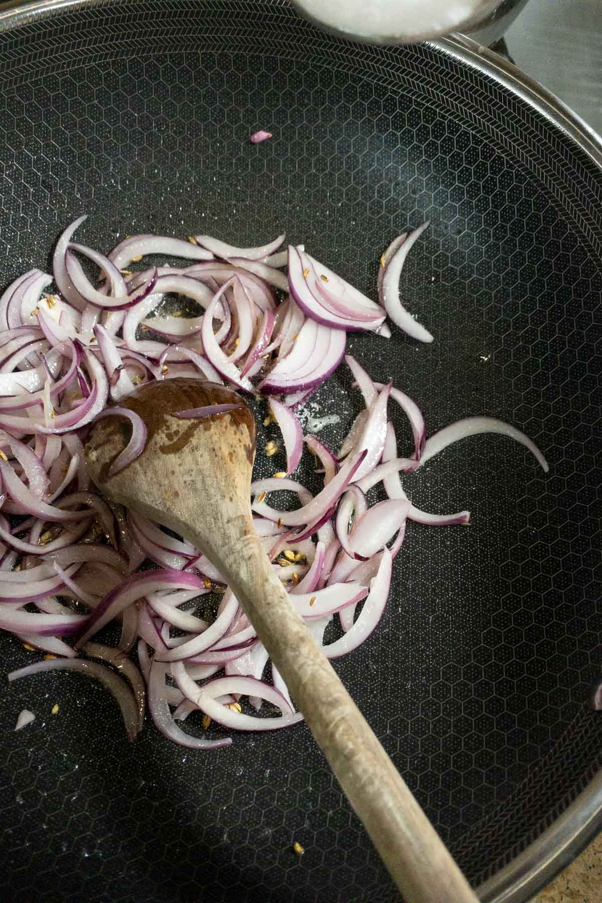 Sauteing the onions to make muttai thokku.