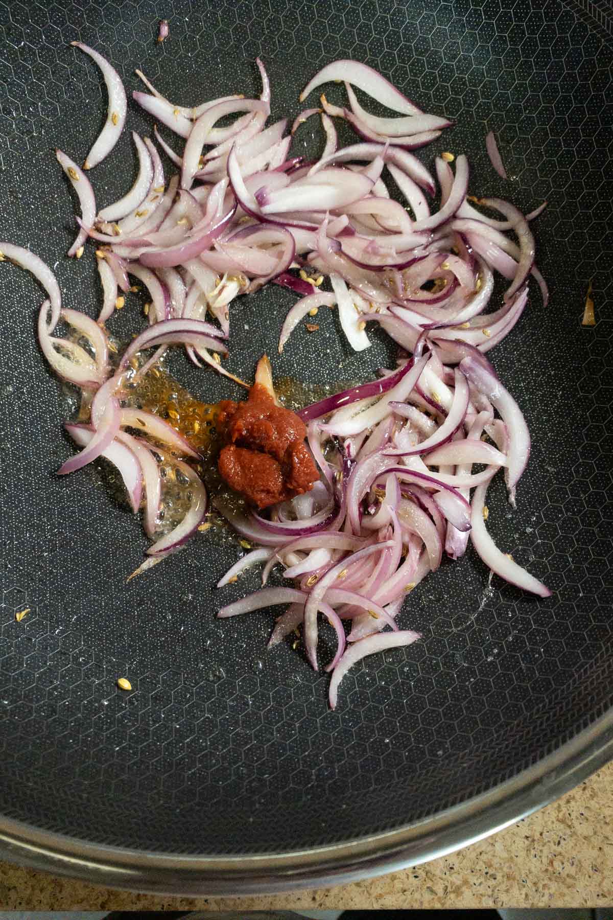 Adding tomato paste to pan.