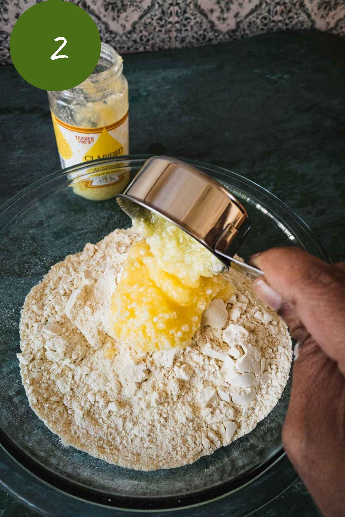 Adding melted ghee to the ground pottukadalai sugar mix.