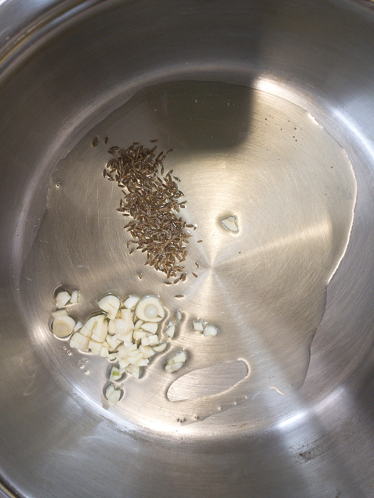 Sauteing cumin and garlic in oil.