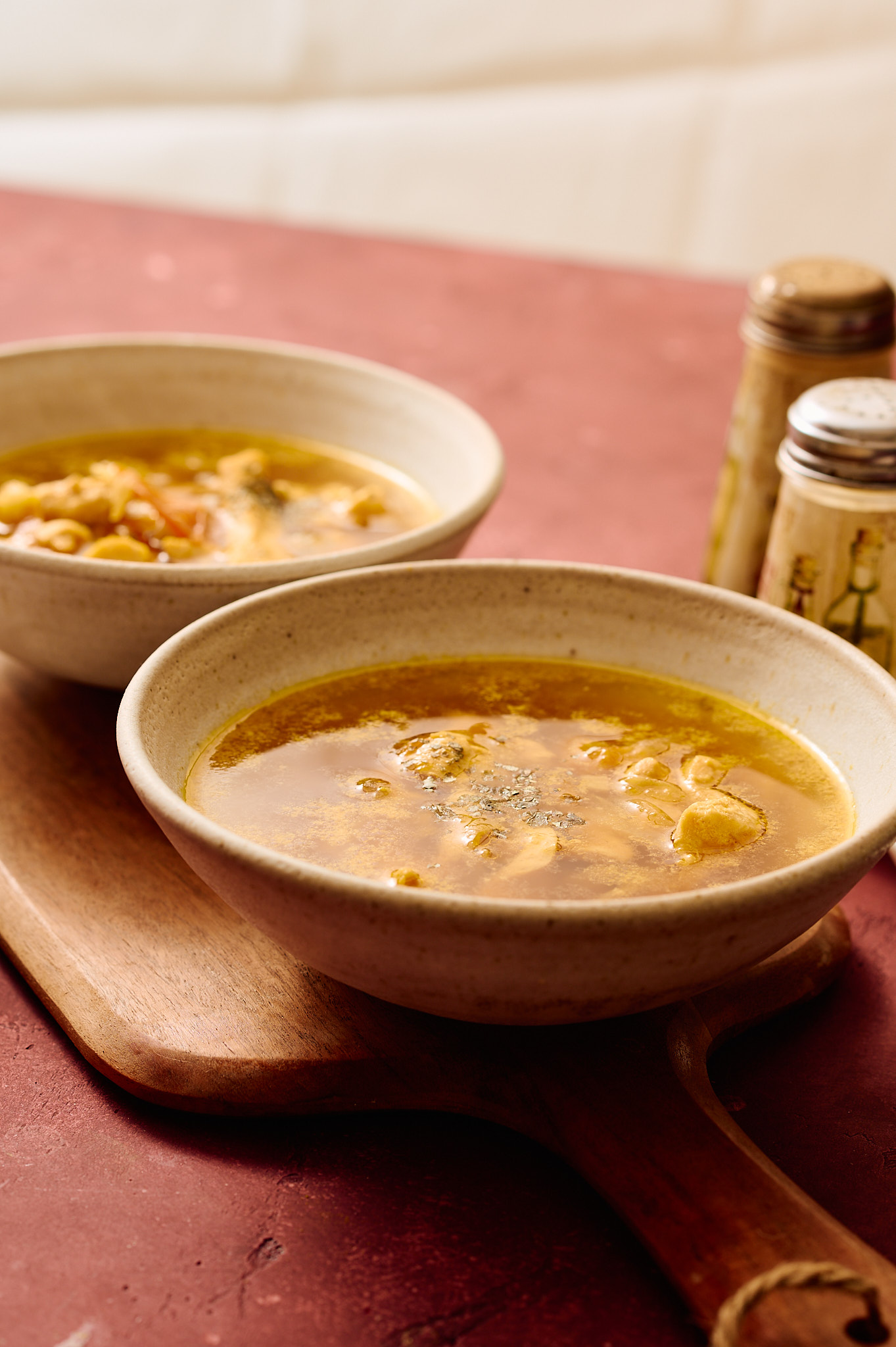 Instant Pot Indian chicken soup served in ceramic bowls, light golden broth with tender chicken, photographed in a warm, rustic setting.